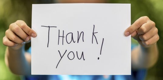 Blurred boy holding a piece of paper with the words Thank You in front of her.