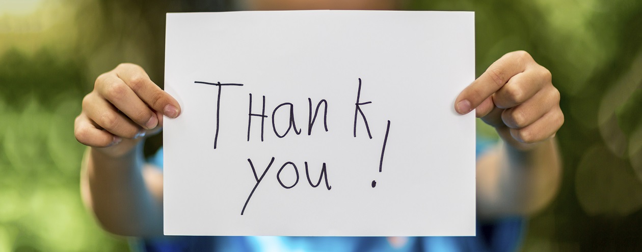 Blurred boy holding a piece of paper with the words Thank You in front of her.